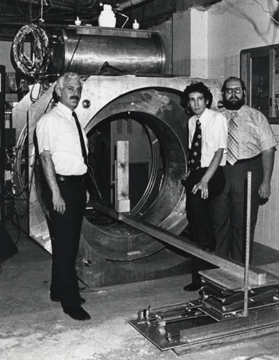 Figure 16. Raymond Damadian, Larry Minkoff and Michael Goldsmith with Indomitable and its iced liquid helium and liquid nitrogen ports: the world's first supercooled, superconducting MR scanner and the world's first MRI machine.